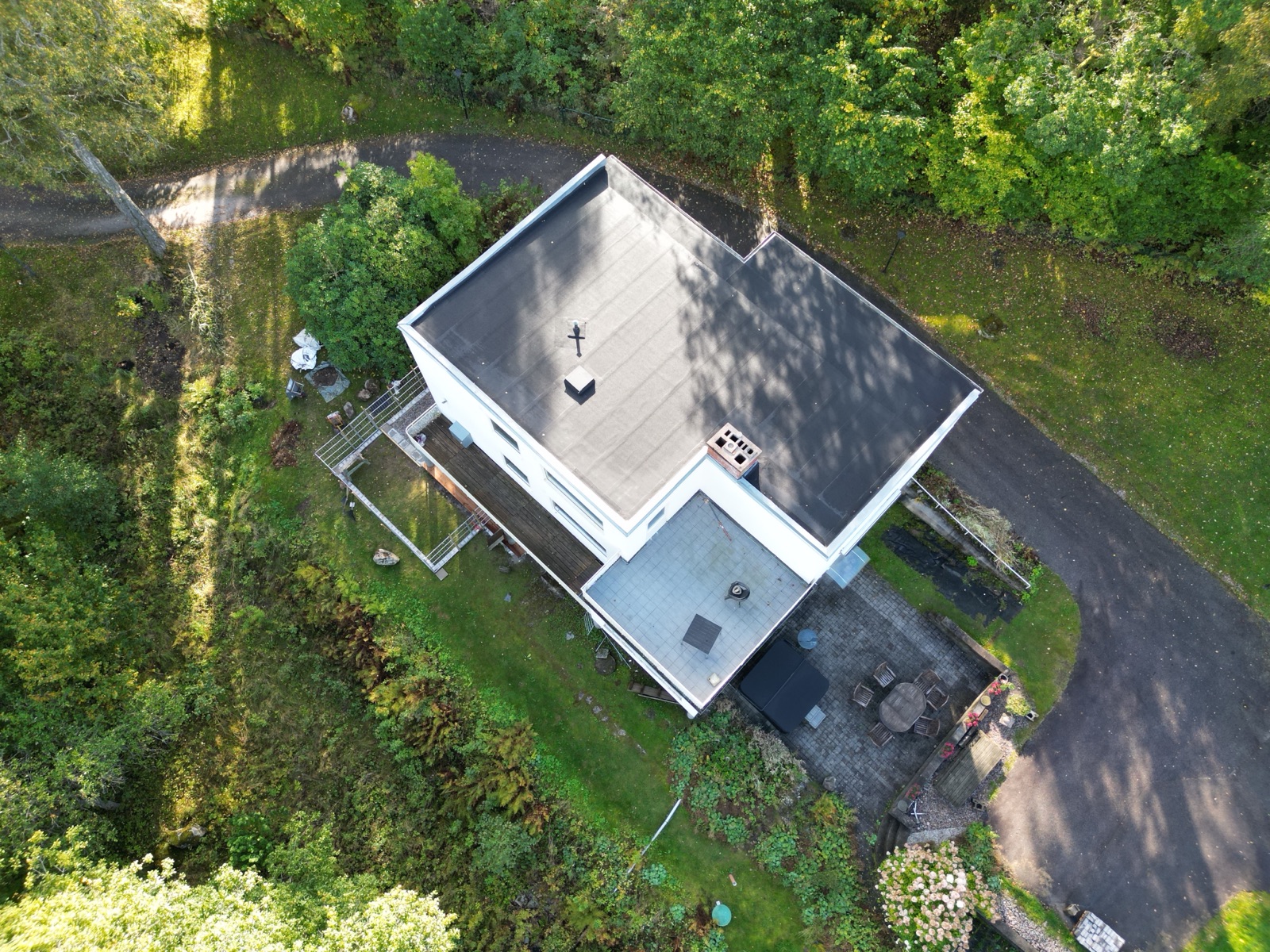 Färdigt låglutande tak med nytt svart tätskikt, ny fotplåt och skorstensanslutning – drönarvy, Hultafors